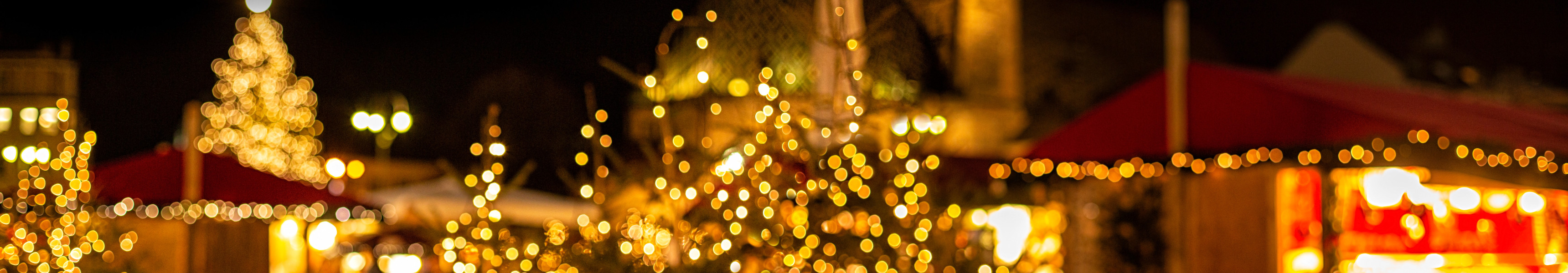 Blick auf einen Weihnachtsmarkt der mit Lichterketten beleuchtet wird