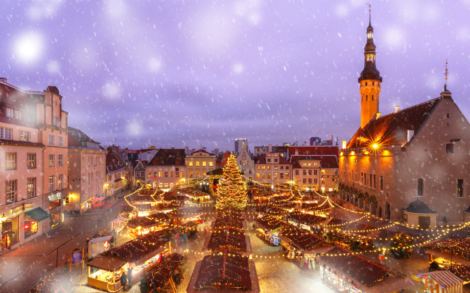 Geschm&uuml;ckter und beleuchteter Weihnachtsbaum sowie Weihnachtsmarkt auf dem Rathausplatz (Raekoja plats) in einer verschneiten Winternacht, Tallinn, Estland. 